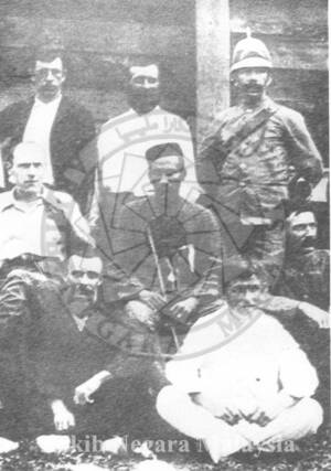 H.C. SYERS BERUNIFORM PENUH (BERDIRI DI SEBELAH KANAN SEKALI) BERSAMA HUGH CLIFFORD DAN RAJA IMPEH (DUDUK DI ATAS KERUSI) DI LOMBONG EMAS STOCKADE, BULAN MEI 1892.